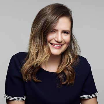 Color photo of woman, Erica, shoulder up smiling for camera.