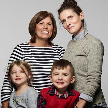 Color photo of woman, named Marina, with her wife and two small children posing for camera.