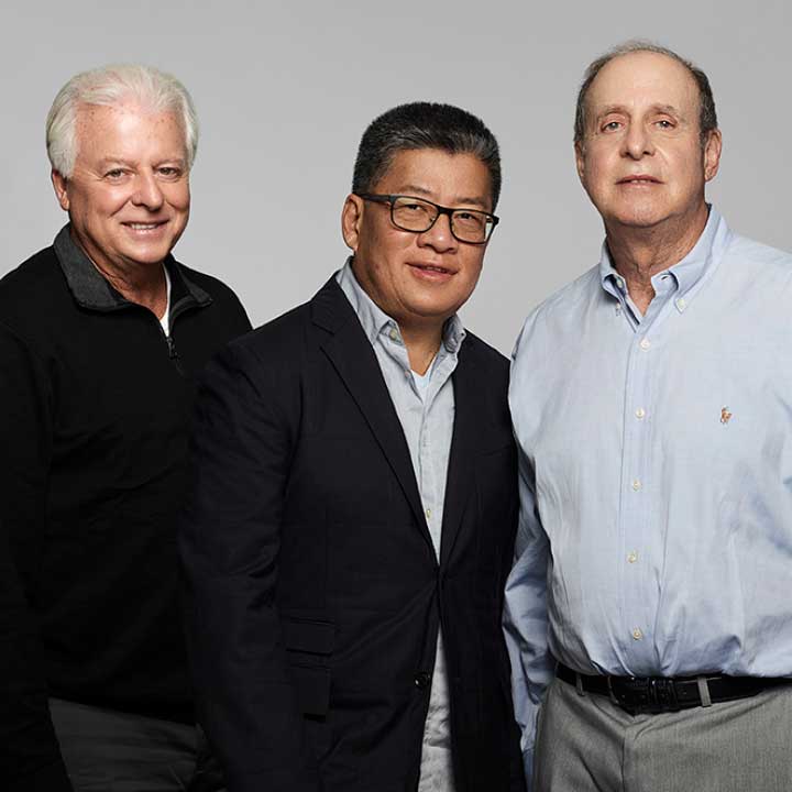 Color photo of 3 men portrait standing waist up, smiling naturally for the camera.