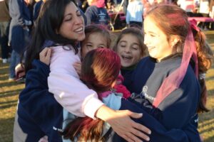 A woman embraces three young girls in a group hug at Making Strides of Long Island 2012
