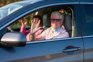 Two people wave and smile gently in car atMaking Strides 2020 Drive Through photo