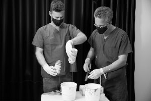 Black and white photo of Dr. Israeli and Dr. Bank focused on preparing the materials that will be painted on models for life cast,