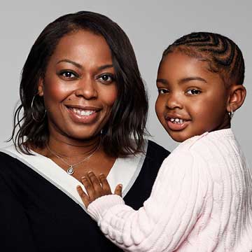 Color photo of woman and child, Donna and her daughter, shoulder up, smiling for the camera.