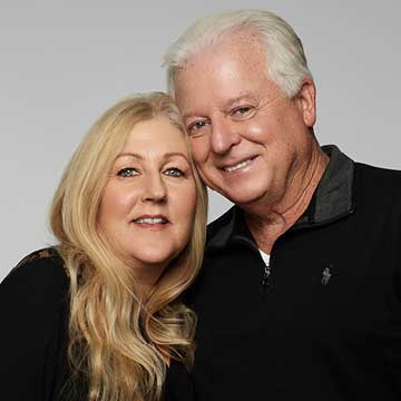 Man and woman posing for camera with gentle smiles. Woman is Lori with blond hair and her husband's head is leaning on hers.