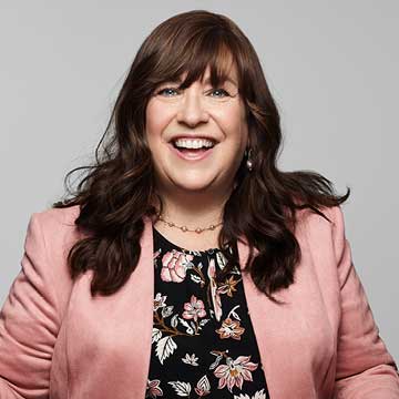 Color photo of woman, Rachel, with shoulder length hair, smiling/half-laughing for the camera.