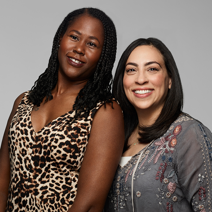 Two women standing closely smiling and posing for color portrait