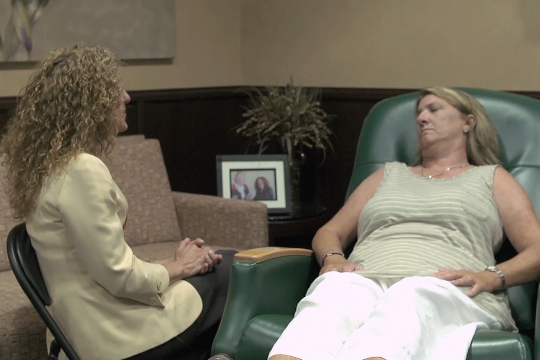 Color image of Mollie Sugarman sitting with patient in chair preparing for guided imagery session.