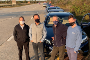 Color photo of Dr. Feingold, Dr. Light, Dr. Israeli and Dr. Bank standing in front of line of cars before Making Strides Drive Through Experience at Jones Beach 2020