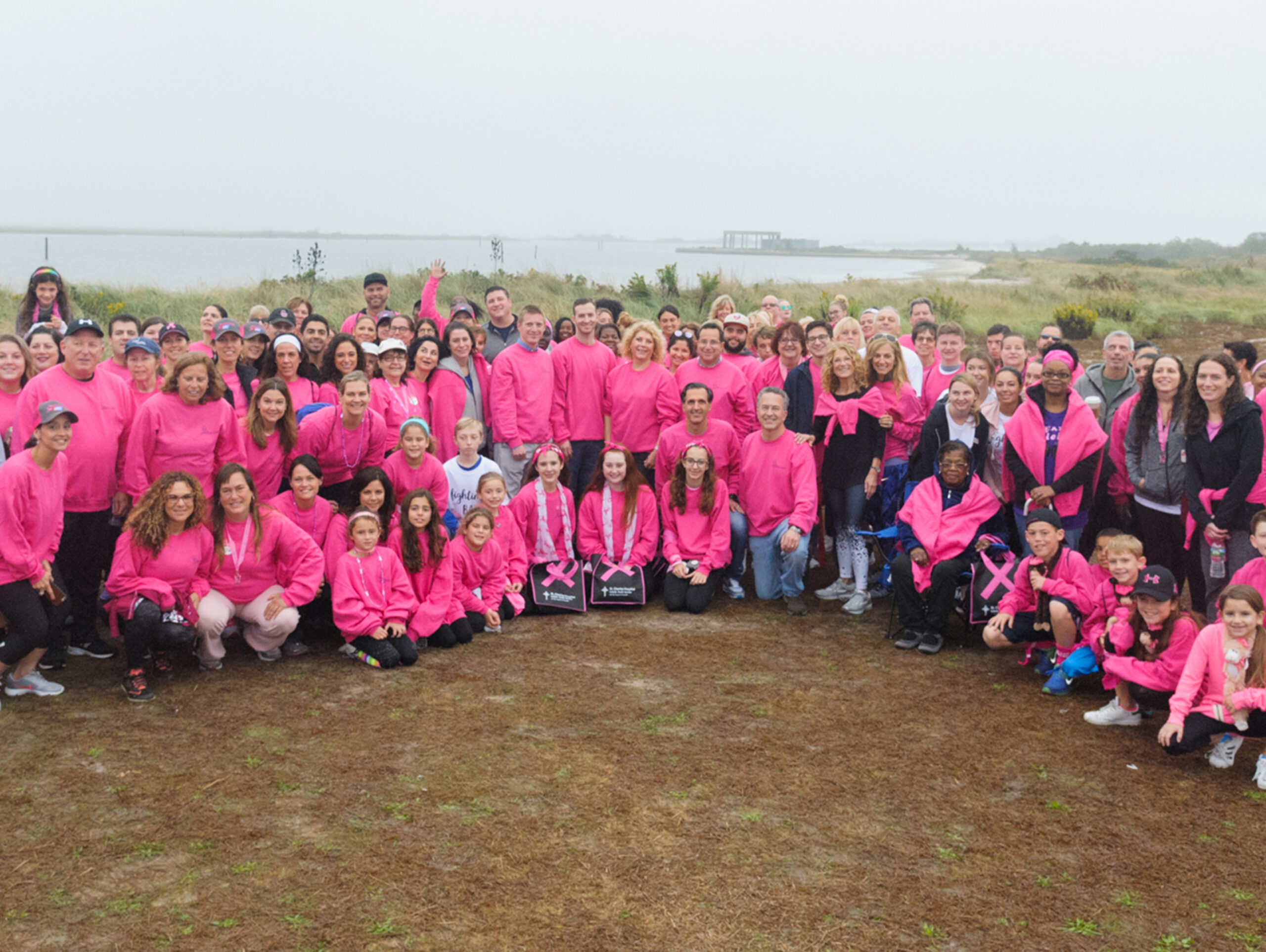 NYBRA Plastic Surgery team in pink sweatshirts pose together for the camera in group shot.