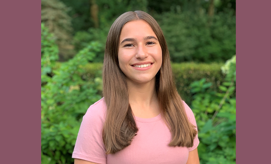 Color photo of teenager smiling at camera.