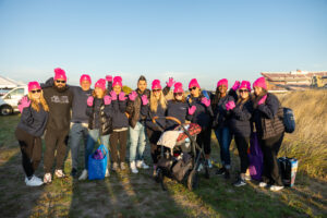 A large group of people wearing hot pink hats stands outside.
