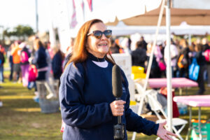 A woman in sunglasses holds a microphone outside